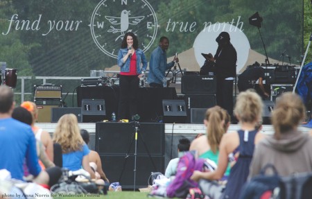 Photo by Anna Norris for Wanderlust Festival. Sage Rountree on stage leading metta meditation. Students sit quietly.
