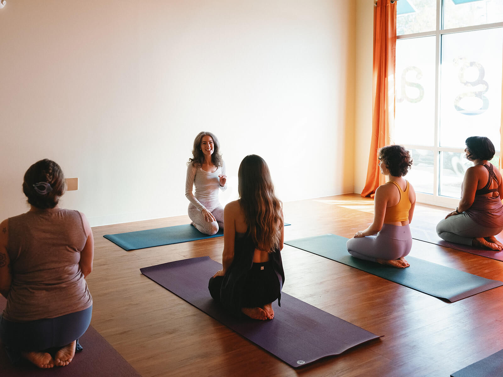 a group of women sitting on mats in a room